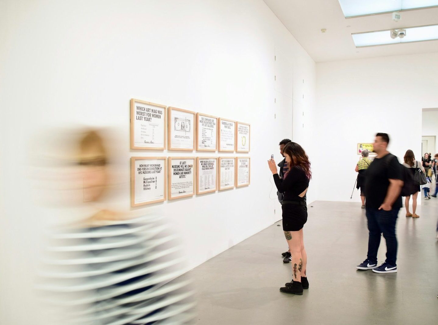 three men and woman standing while looking at bulletin board